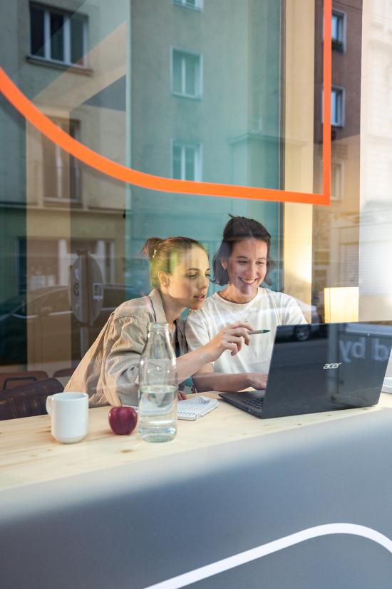 Zwei Frauen sitzen am Fenster mit Laptop und arbeiten