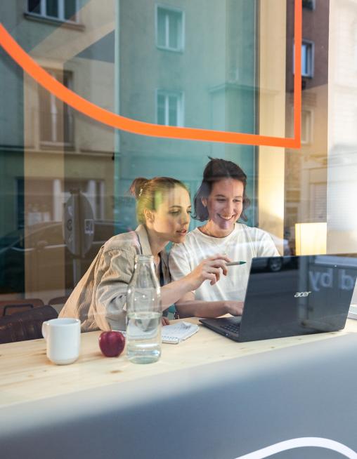 Zwei Frauen sitzen am Fenster mit Laptop und arbeiten